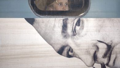 Una niña mira desde la ventana de un tren hacia el anuncio de una exposición sobre Salvador Dalí en Bucarest (Rumanía), el 29 de marzo de 2024.