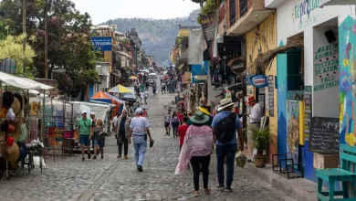Turistas caminan por una calle comercial con montañas a la distancia, en Tepoztlán, estado de Morelos, México