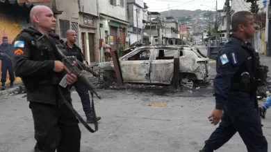 Policías junto a un coche quemado durante un operativo policial contra el Comando Vermelho en la favela Complexo do Alemao. Río de Janeiro