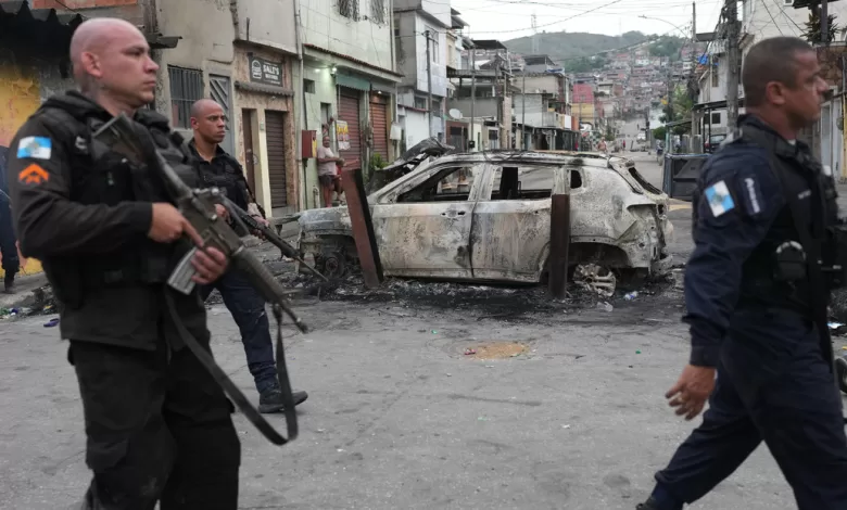 Policías junto a un coche quemado durante un operativo policial contra el Comando Vermelho en la favela Complexo do Alemao. Río de Janeiro