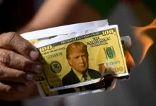 Un protestante quema un billete de dólar falso con la cara de Donald Trump en una manifestación en Brasil contra los aranceles